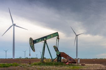 caption: An oil pump jack stands near a field of wind turbines in Nolan, Texas, on Oct. 4. Oil companies are under pressure to pivot more swiftly toward renewable energy. Here's one reason why that's not happening so quickly: It's still incredibly lucrative to sell oil.