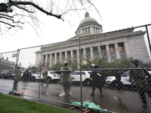 caption: Members of the Washington National Guard stand near a fence surrounding the Capitol in Olympia, Wash., in anticipation of protests on Jan. 11, 2021.