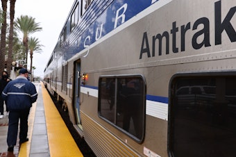 caption: An Amtrak worker and train are pictured on Dec. 9, 2021, in Fullerton, Calif. The company reached a settlement after the Justice Department said Amtrak failed to make stations in its intercity rail transportation system accessible, including to wheelchair users.