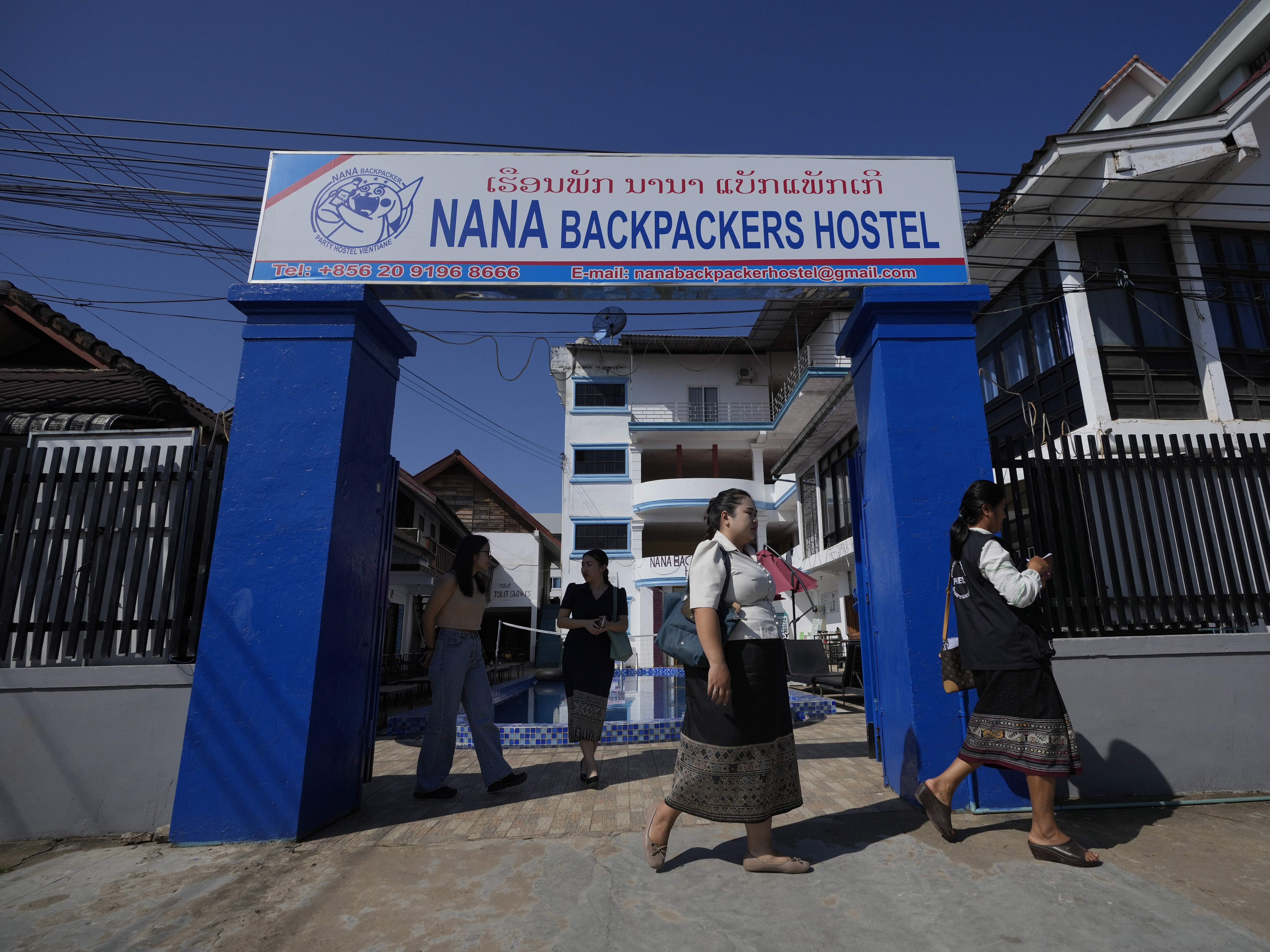 caption: Health officials come out of Nana Backpackers Hostel after checking documents in Vang Vieng, Laos, on Friday.