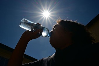caption: A child sips water from a bottle under a scorching sun on Tuesday in Los Angeles. Forecasters say temperatures  could reach as high as 112 degrees in the densely populated Los Angeles suburbs in the next week as a heat dome settles in over parts of California, Nevada and Arizona.