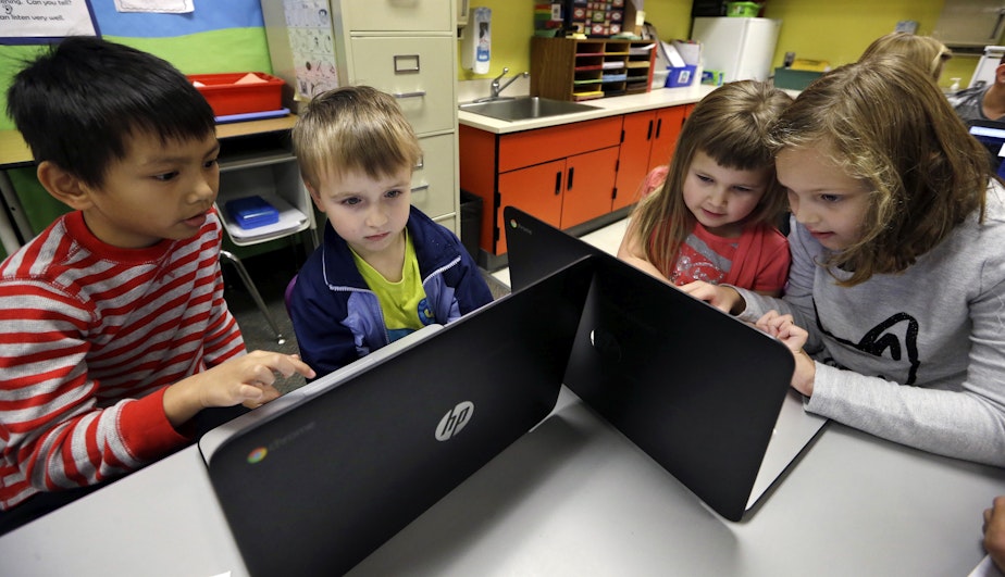 caption: In this photo taken Nov. 4, 2015, second grader Josh Mercado, left, helps kindergartner Erik Hodges, as second grader Annabelle Davis, right, helps kindergartner Kaidyance Harris, on programming during their weekly computer science lesson at Marshall Elementary School in Marysville, Wash.