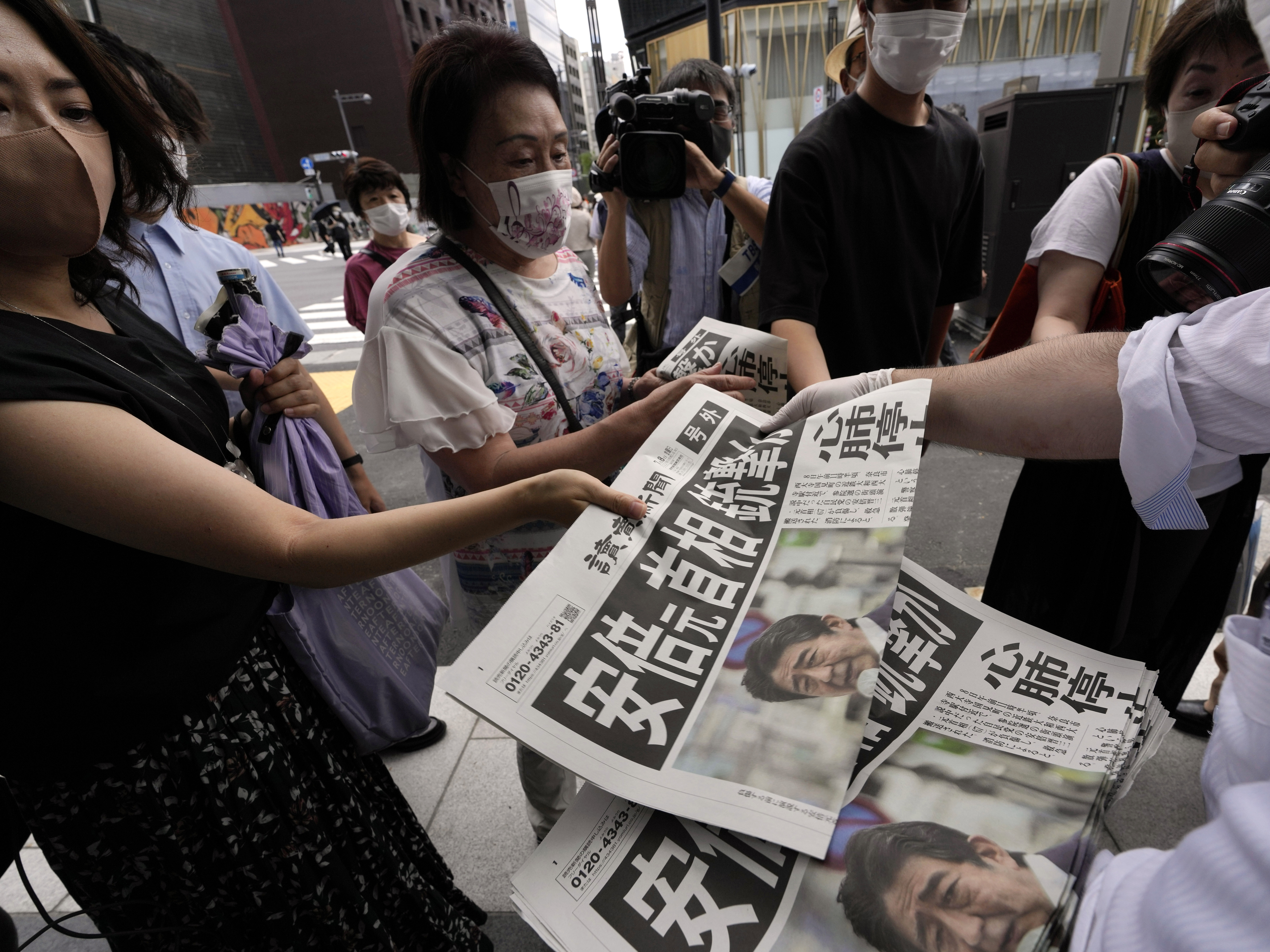 caption: An employee of the Yomiuri Shimbun distributes extra editions of the newspaper in Tokyo with reporting on the shooting of Japan's former Prime Minister Shinzo Abe on Friday.