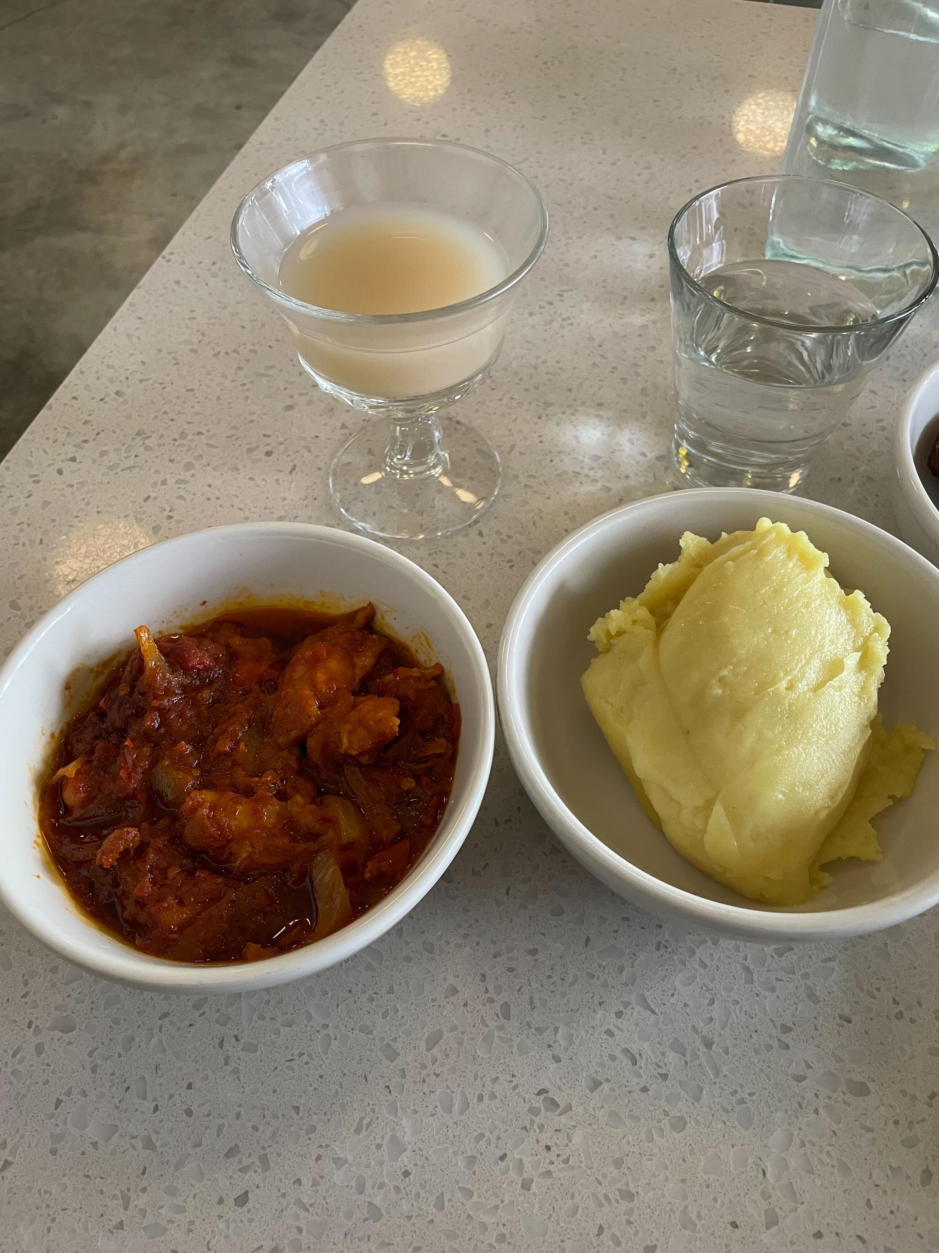 caption: Chicken stew served with fufu and palm wine.