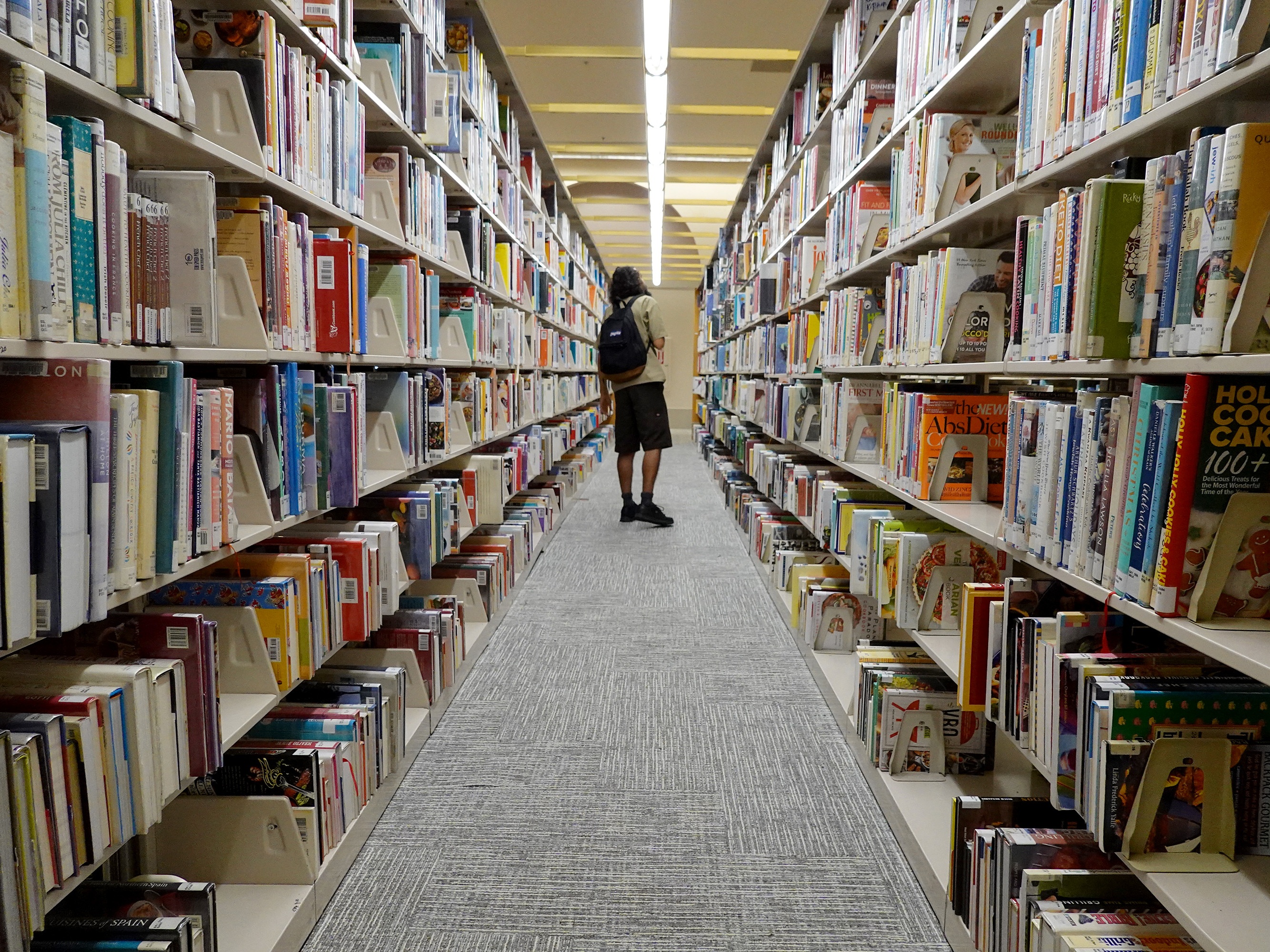 caption: Searching the stacks at a Miami-Dade Public Library on July 19, 2023, in Miami.