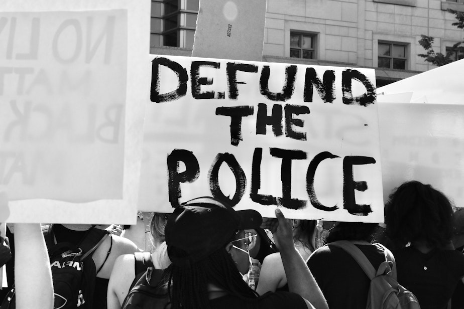 An anti-police brutality protester holds a sign that calls to defund the police