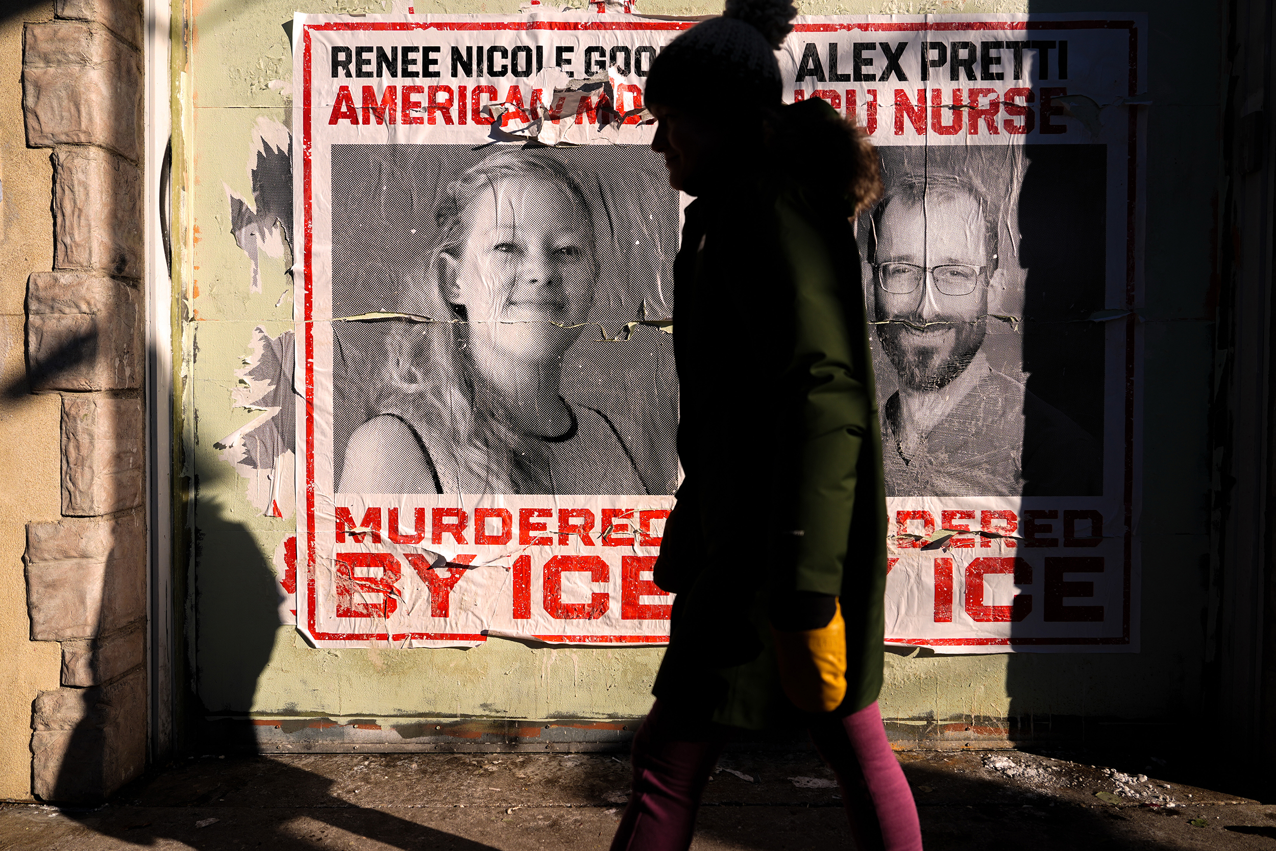 caption: A woman walks by posters of Renee Good and Alex Pretti during a solidarity bike ride for Pretti, Saturday, Jan. 31, 2026, in Minneapolis. 