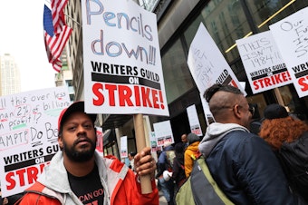 caption: Members of the Writers Guild of America (WGA) East picketed outside of the Peacock NewFront on May 2, 2023 in New York City as the WGA strike began.