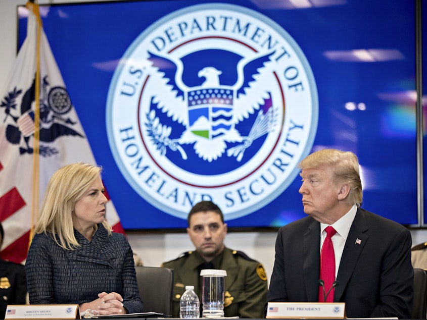 caption: Then-President Donald Trump and the Homeland Security secretary at the time, Kirstjen Nielsen, speak during a Customs and Border Protection roundtable in Virginia in 2018. The Biden administration rescinded an agreement from that time between the Homeland Security and Health and Human Services departments that it says hampered efforts to find safe homes for unaccompanied minors.
