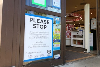 caption: The sign in front of a Seattle drug store attempting to mitigate contact with cases of Covid-19. 