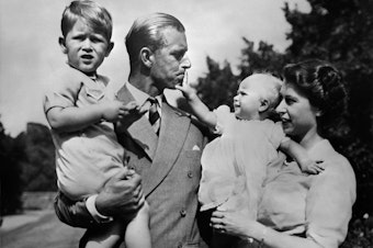 caption: Philip and Elizabeth carry around their eldest children, Prince Charles and Princess Anne, circa 1951.