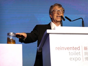 caption: Bill Gates, co-founder of the Bill & Melinda Gates Foundation, gestures to a jar of human feces as he speaks at the Reinvented Toilet Expo in Beijing on November 6.