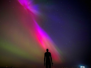 caption: Crosby Beach, Liverpool, England: The aurora borealis, also known as the northern lights, glow on the horizon at Another Place by Anthony Gormley.