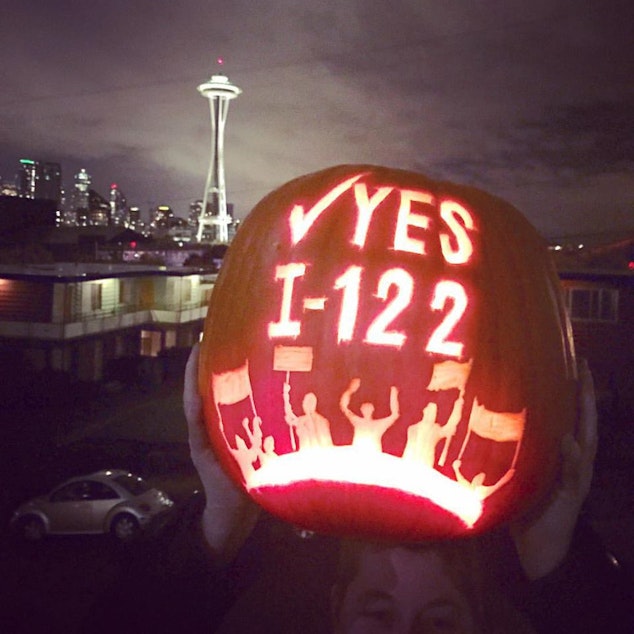 caption: A supporter of Initiative 122 displays a carved pumpkin.