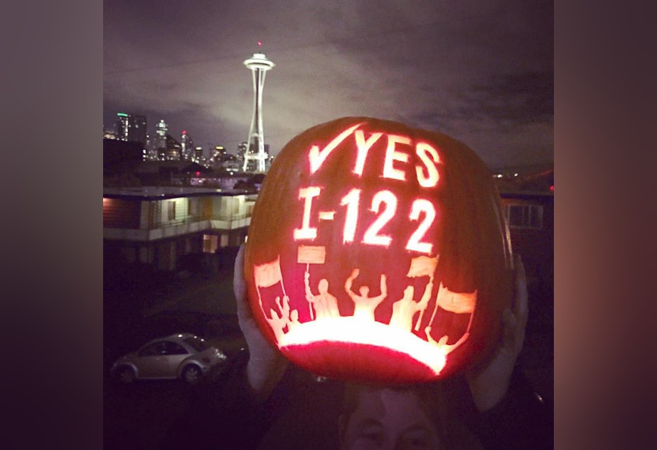 caption: A supporter of Initiative 122 displays a carved pumpkin.