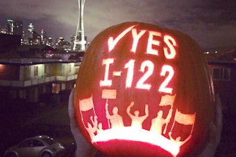caption: A supporter of Initiative 122 displays a carved pumpkin.