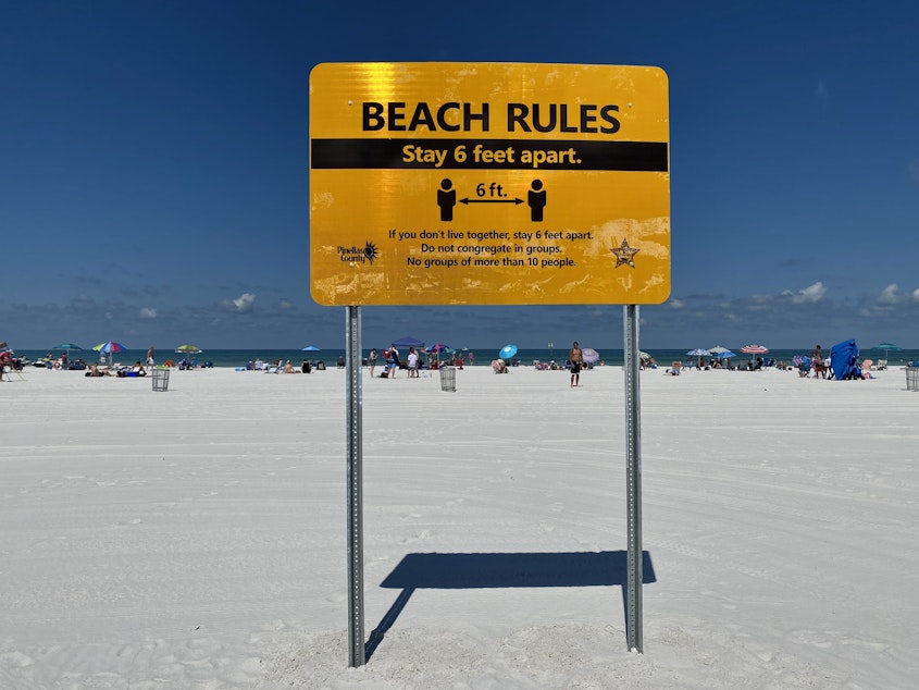 caption: Clearwater Beach opened to the public on Monday with signs warning beachgoers to practice social distancing.