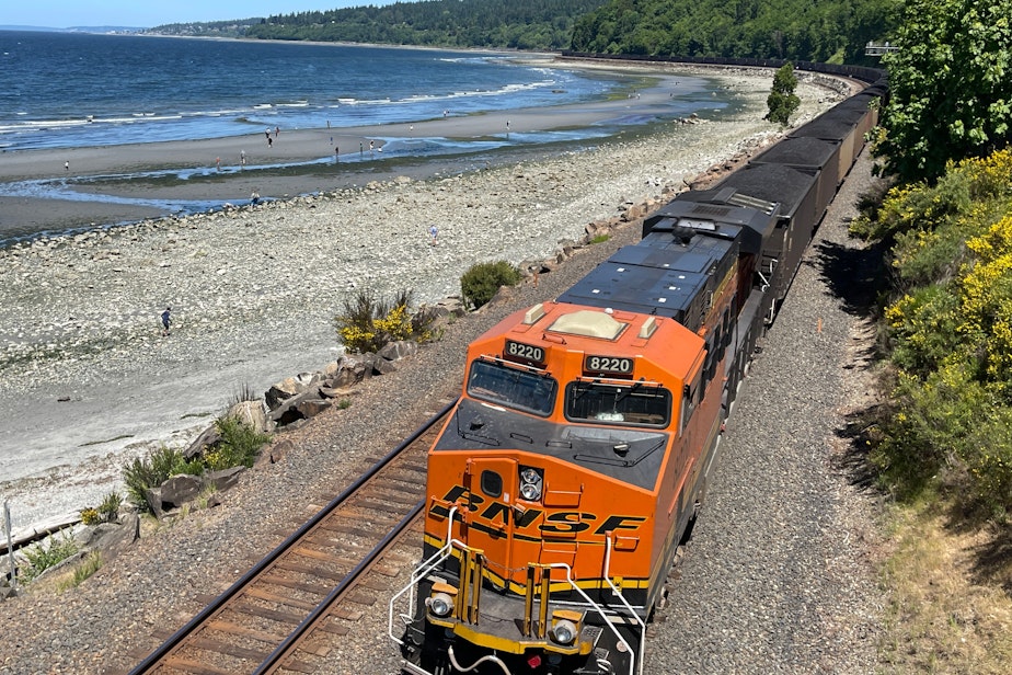 caption: A mile-long BNSF Railway coal train winds its way through Seattle's Carkeek Park in June 2023.