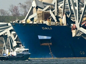 caption: The wreckage of the collapsed Francis Scott Key Bridge lies on top of the container ship Dali in Baltimore, Maryland, on March 29, 2024.