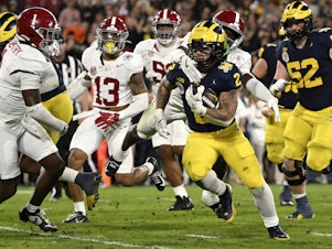 caption: Michigan running back Blake Corum (2) runs in for a touchdown past Alabama defensive back Kool-Aid McKinstry (1) during overtime at the Rose Bowl CFP NCAA semifinal college football game Monday, Jan. 1, 2024, in Pasadena, Calif.