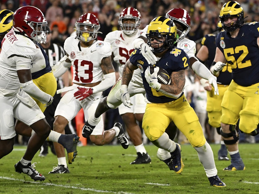 caption: Michigan running back Blake Corum (2) runs in for a touchdown past Alabama defensive back Kool-Aid McKinstry (1) during overtime at the Rose Bowl CFP NCAA semifinal college football game Monday, Jan. 1, 2024, in Pasadena, Calif.