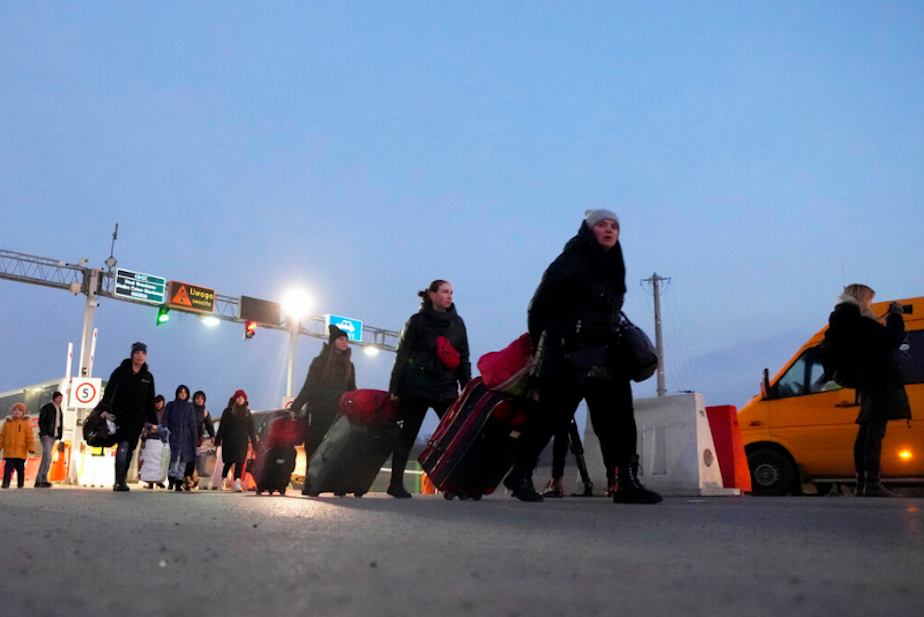 caption: Displaced persons carry luggage as they walk to a border crossing in Medyka, Poland, Thursday, March 3, 2022. More than 1 million people have fled Ukraine following Russia's invasion in the swiftest refugee exodus in this century, the United Nations said Thursday. 