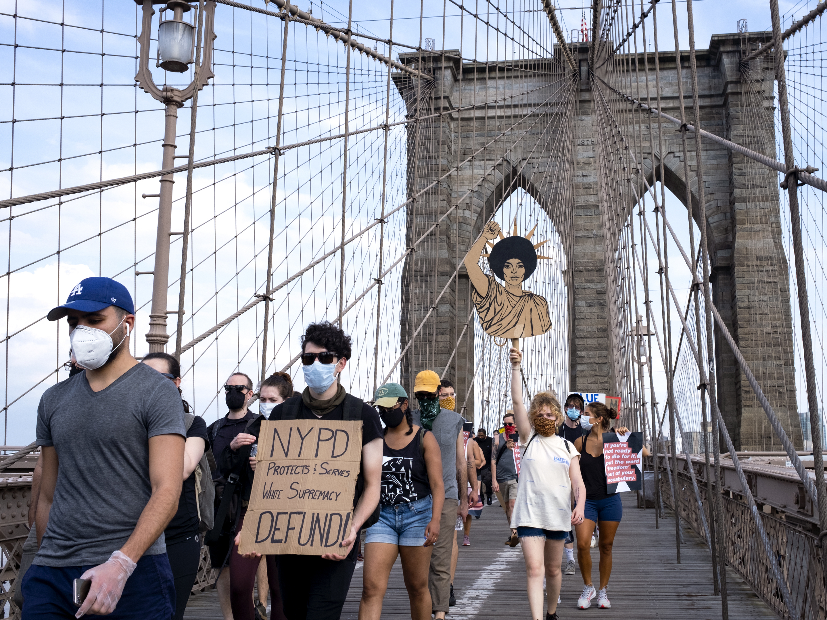 caption: Protesters and activists walk across the Brooklyn Bridge Saturday in New York. Cities saw some of their biggest gatherings of the past two weeks on Saturday.