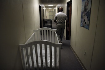 caption: A federal employee walks past cribs inside of the barracks of a family detention center in Artesia, New Mexico, for those crossing the border. This photo is from 2014, when attorney Danielle RoschÃ© volunteered there.