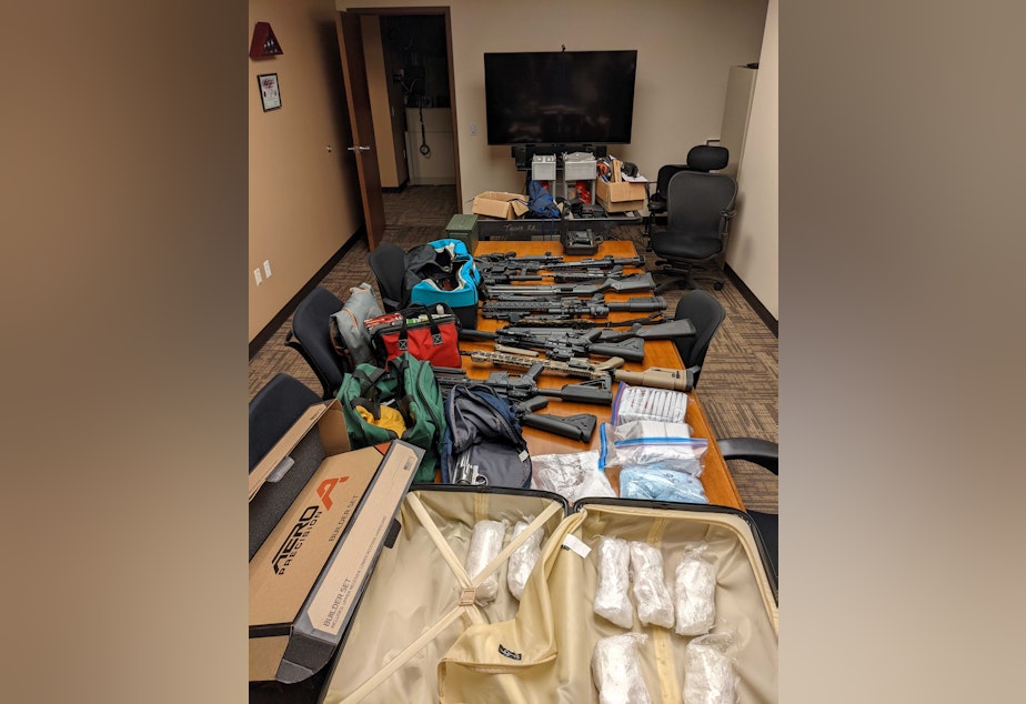 caption: Items captured as part of the investigation include 19 firearms, 3,372 grams of suspected methamphetamine, 1,322 grams of suspected fentanyl-laced pills, and more than $210,000.