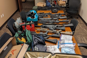 caption: Items captured as part of the investigation include 19 firearms, 3,372 grams of suspected methamphetamine, 1,322 grams of suspected fentanyl-laced pills, and more than $210,000.