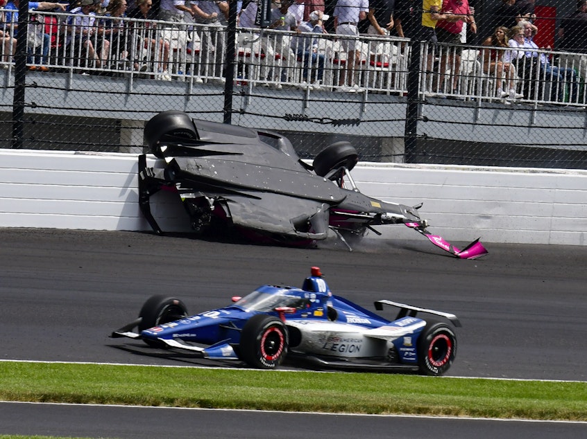 caption: The car driven by Kyle Kirkwood, top, flips over after a crash in the second turn during the Indianapolis 500 auto race at Indianapolis Motor Speedway on Sunday.