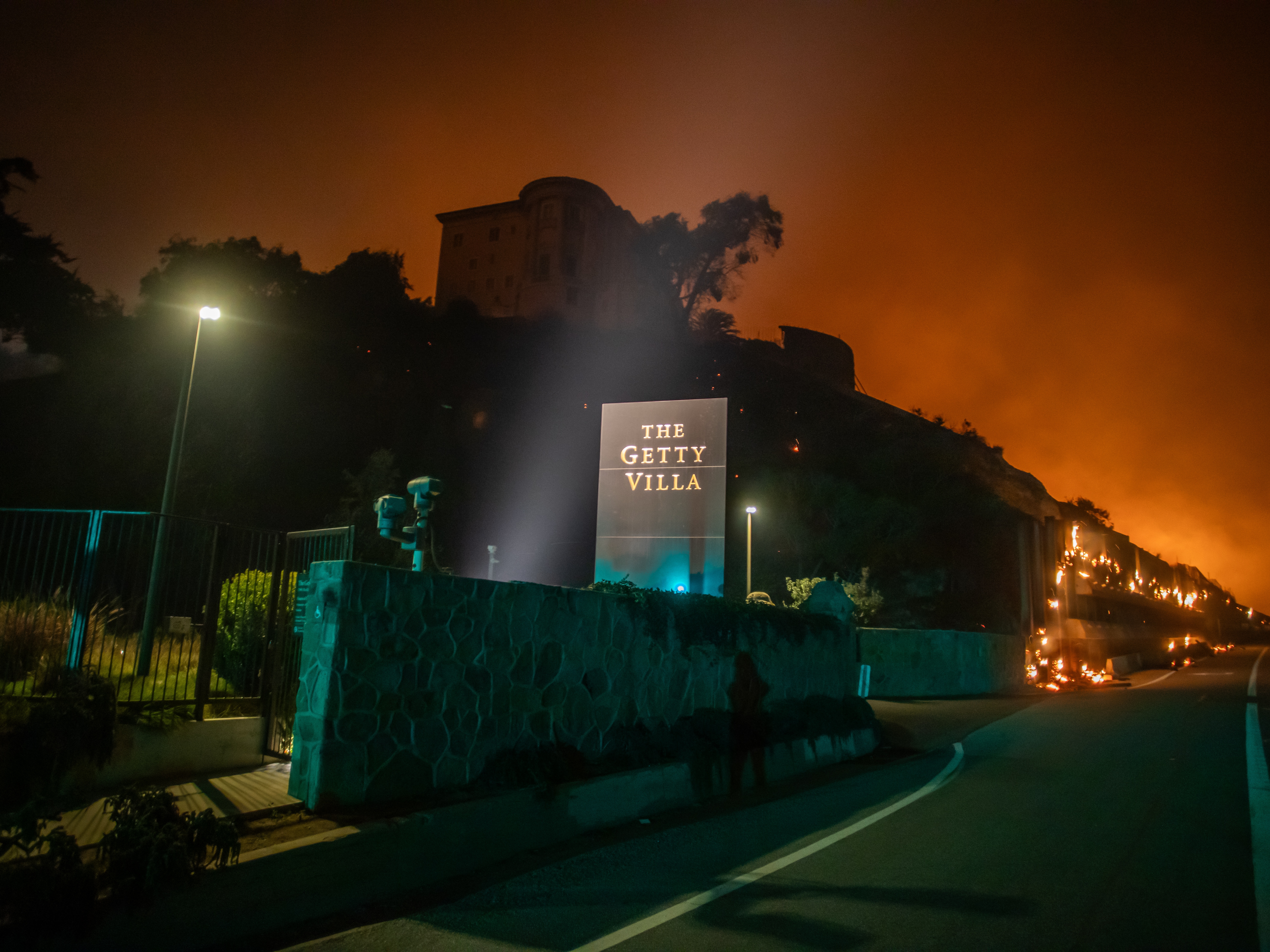 caption: Flames from the Palisades Fire reach the grounds of the Getty Villa Museum on the Pacific Coast Highway amid a powerful windstorm on January 8, 2025 in Los Angeles, California. The museum was forced to close for around six months, causing a major drop in annual visitorship numbers for 2025.