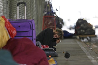caption: In this Oct. 12, 2017 photo, Dominic, who battles mental illness, sits on a sidewalk under the Smith Ave. Bridge in Everett, Wash., which is a constant gathering place for homeless people battling addiction and mental illness. 