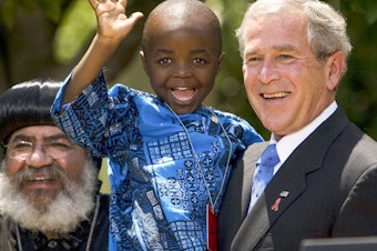 caption: In 2003, President George W. Bush created PEPFAR to help countries tackle the HIV/AIDS crisis. Four years later, he spoke at the Rose Garden to urge lawmakers to set aside $30 billion for the cause over the next 5 years. Joining him were Kunene Tantoh of South Africa and her 4-year-old son (pictured). Tantoh, who is HIV-positive, coordinated a U.S.-funded mentoring program for mothers with HIV.