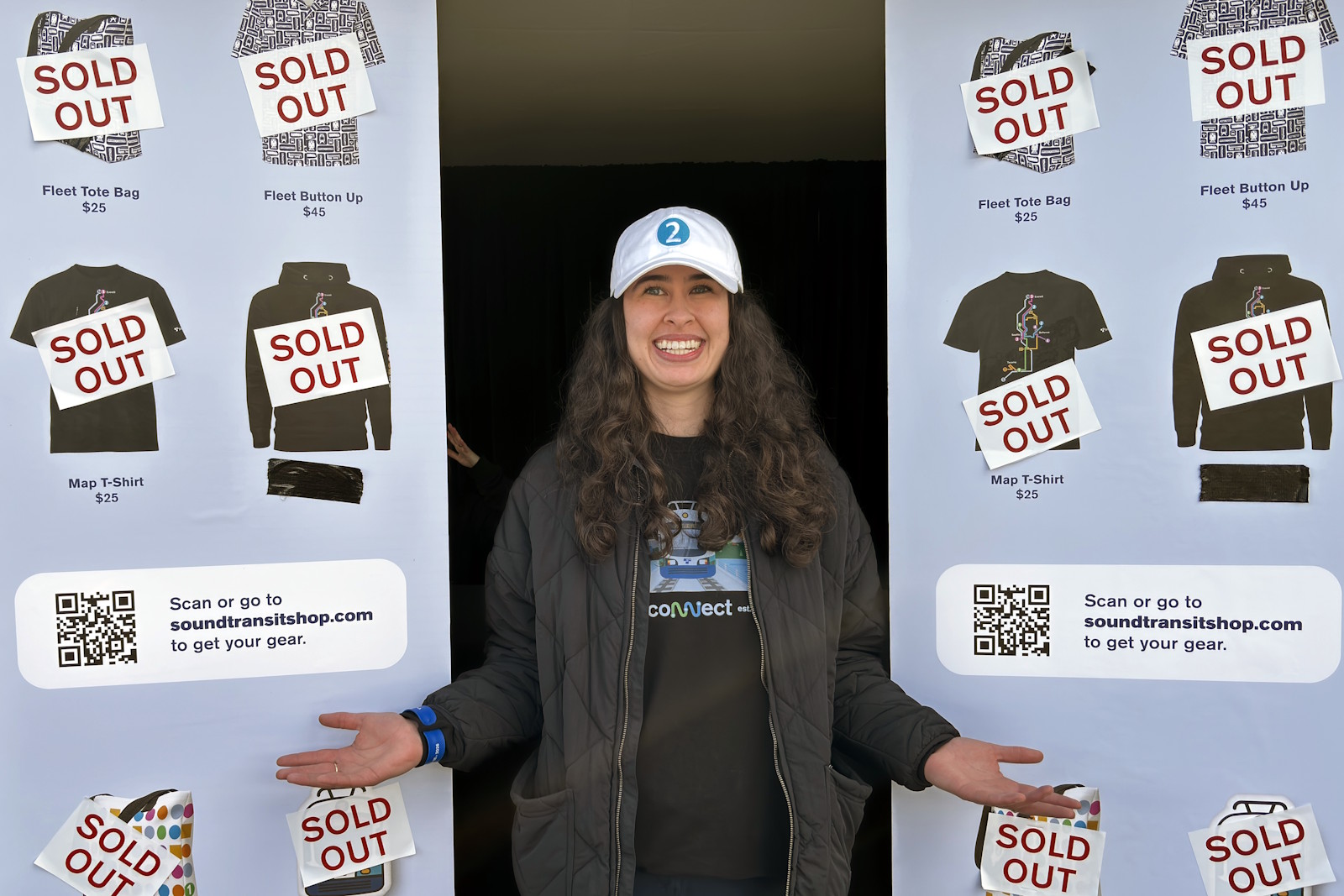 caption: Kelsey Hay, manager of the merch tent at Judkins Park Station, says all 691 pieces of Sound Transit merchandise sold out long before the day's event was over.