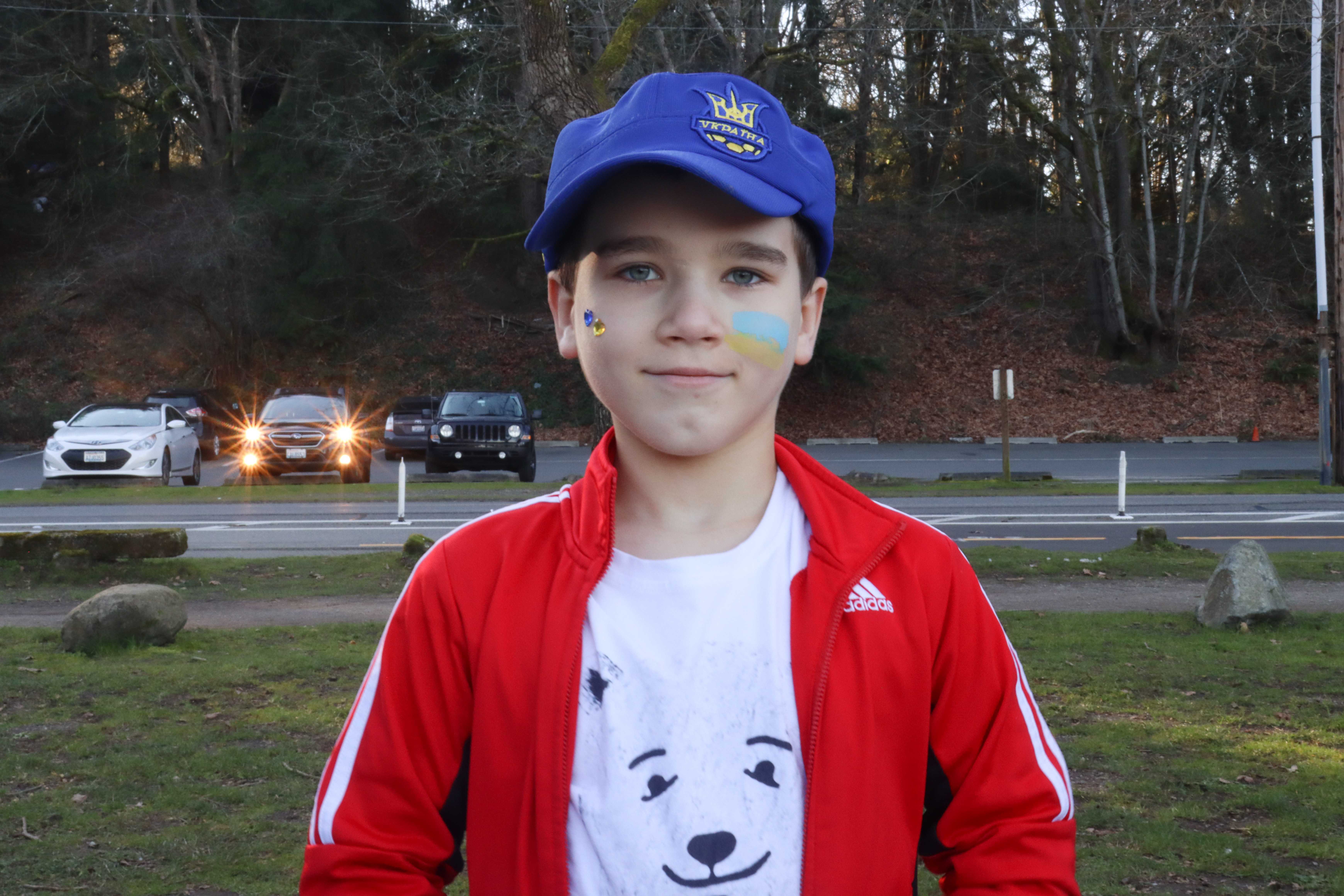 caption: Darii Piskor looks at the camera. He has the colors of the Ukranian flag painted on his cheek.