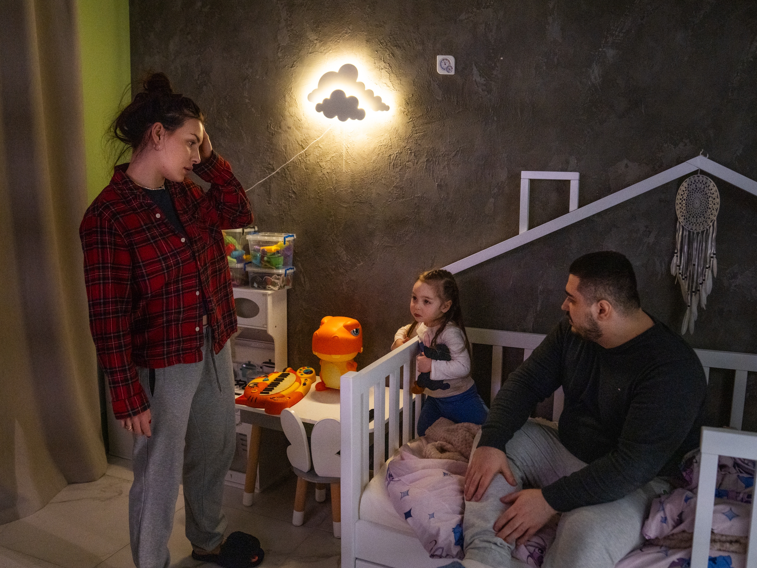 caption: Hanna and Arkadii Rubin try to convince their daughter Leya, 2, to go to bed, although she doesn't want to. They live in an apartment in Kharkiv where, just over a year ago, part of the building was damaged in a missile attack.