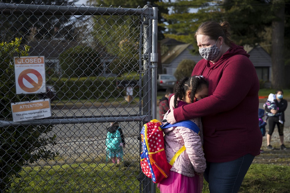 caption: Alayna Holmes, a first-grade student at Northgate Elementary School, hugs her mom, Michelle Holmes, while saying goodbye on Monday, April 5, 2021, on the first day of in-person learning at the school in Seattle. 