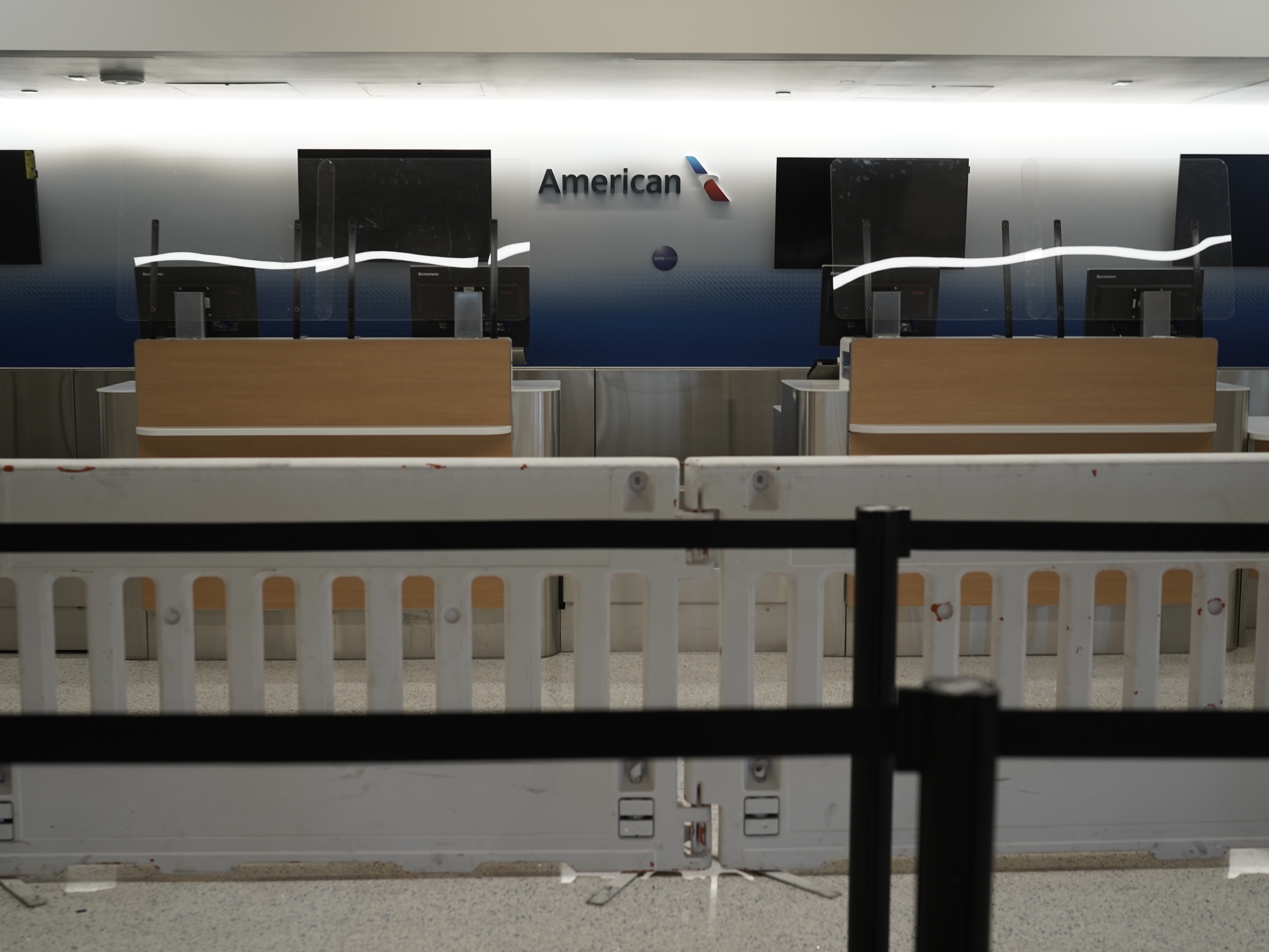 caption: American Airlines check-in counters sit closed last month behind plastic barriers at Los Angeles International Airport.