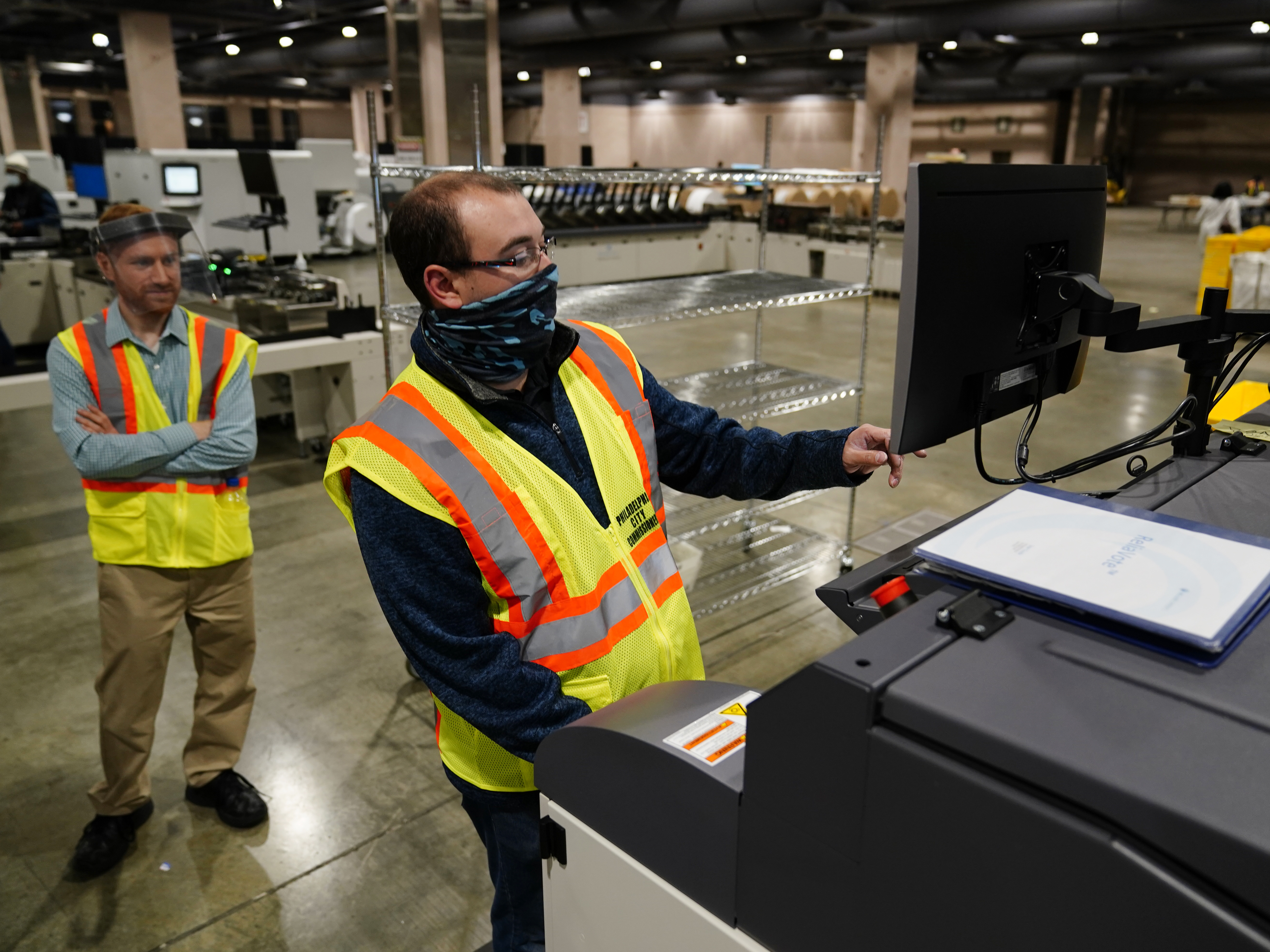 caption: John Hansberry with the Philadelphia City Commissioners Office runs a sorting machine at the city's mail-in ballot sorting and counting center on Oct. 26.