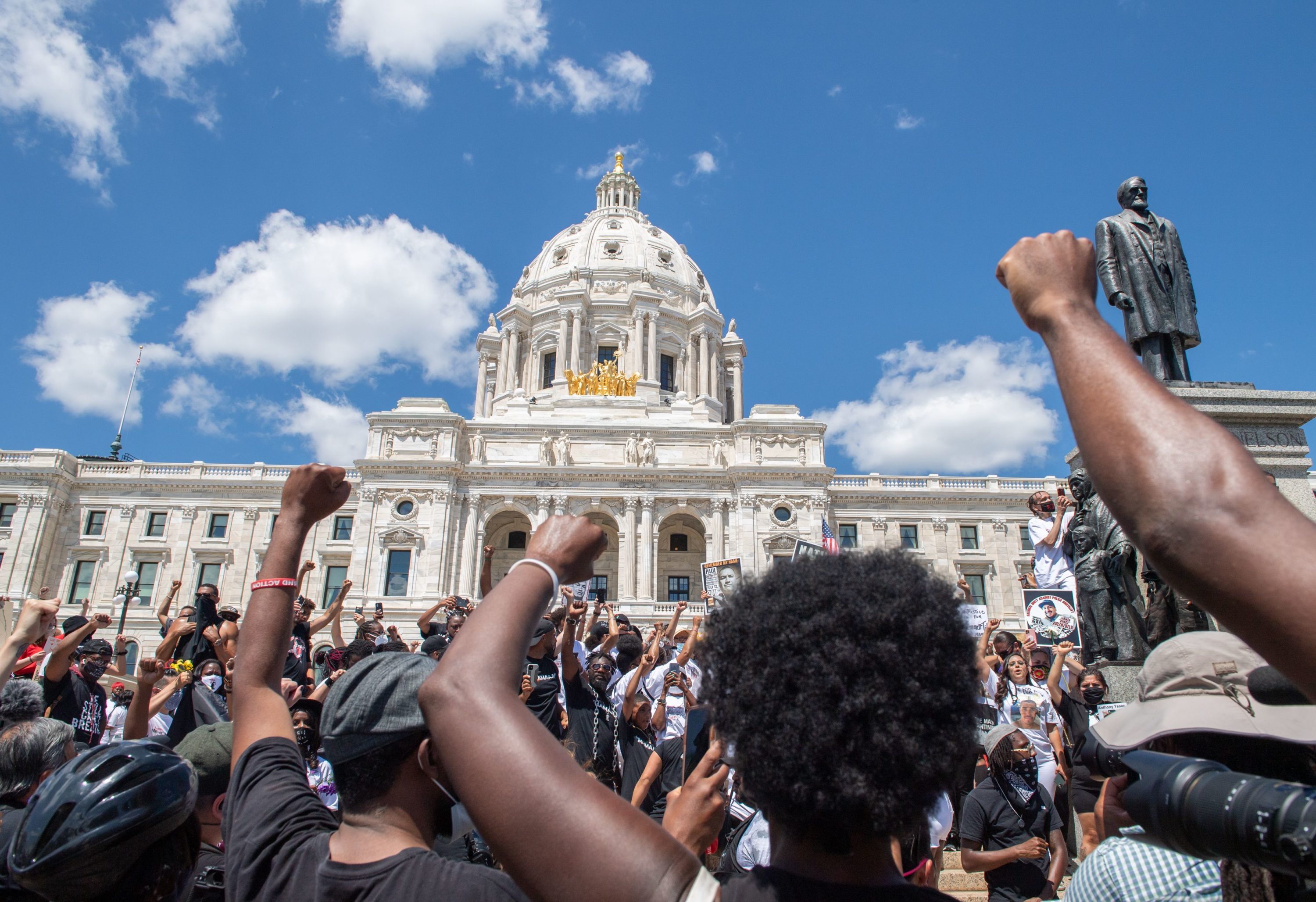 caption: Supporters raise their fists while standing at the State Capitol during a National Mother's March in St. Paul, Minnesota July 12, 2020. (Amanda Sabga/AFP via Getty Images)