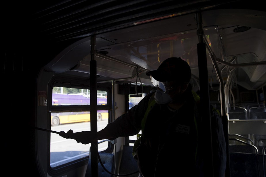 caption: Larry Bowles, an equipment service worker with King County Metro, sprays a Virex II cleaning solution on the interior of a King County metro bus on Wednesday, March 4, 2020, at the Atlantic Base on 6th Avenue South in Seattle. 
