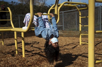 caption: Mialisa Celestin, a kindergarten student at Jackson Elementary, hangs upside down on the playground during recess on Tuesday, March 23, 2021, at Jackson Elementary School along Federal Avenue in Everett. 