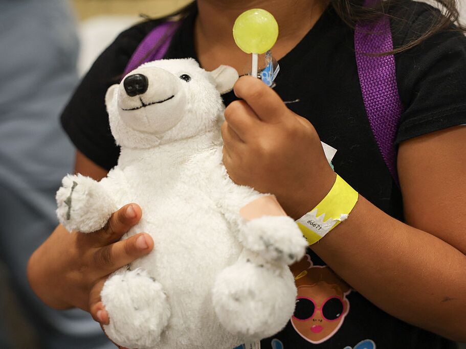 caption: A child holds a toy bear with a band-aid after receiving a flu shot during an immunization event in Los Angeles. Flu is one of six vaccines that will no longer be given routinely but now require a consultation with a doctor.