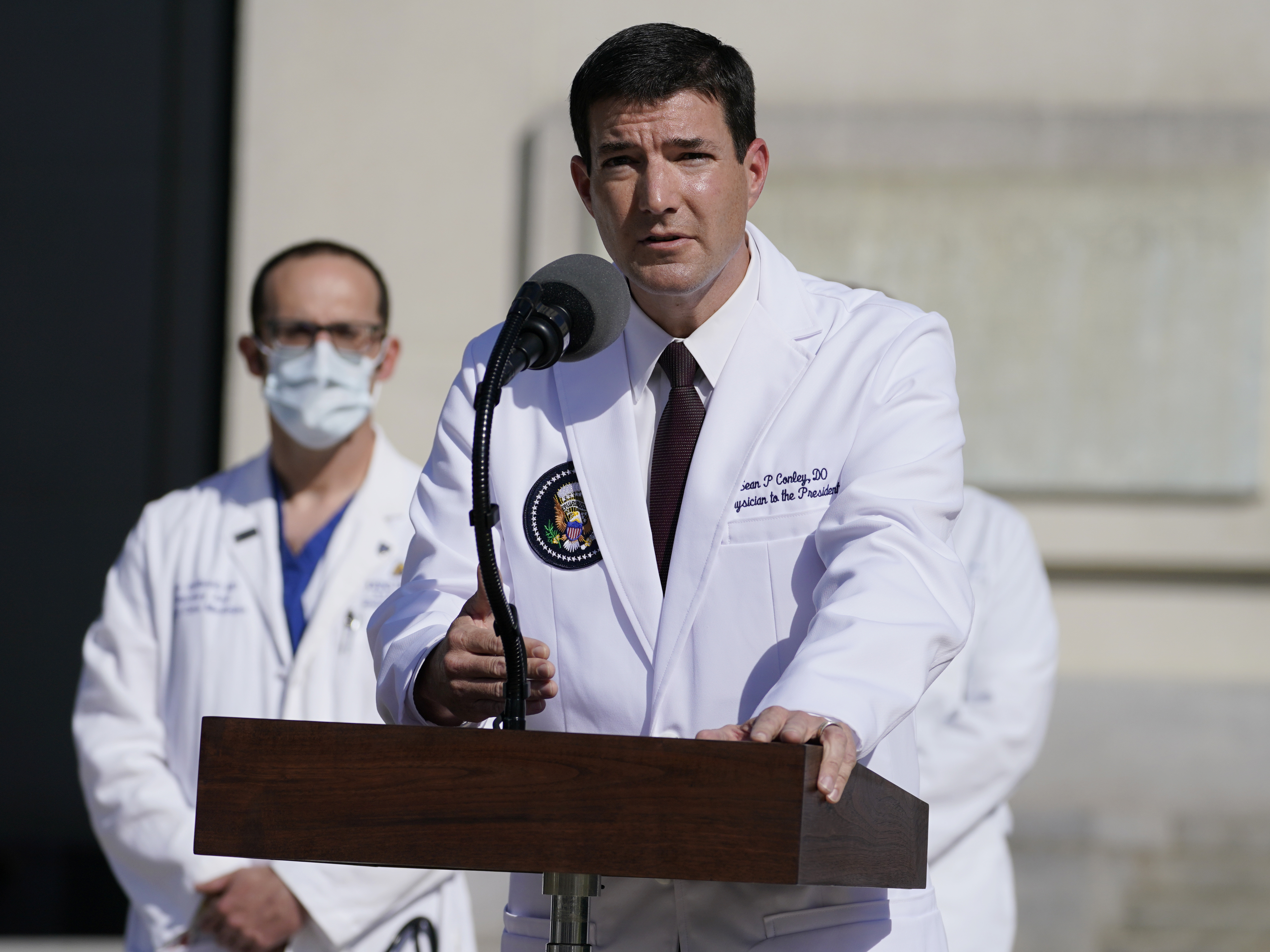 caption: Dr. Sean Conley, physician to President Trump, talks with reporters at Walter Reed National Military Medical Center on Monday.