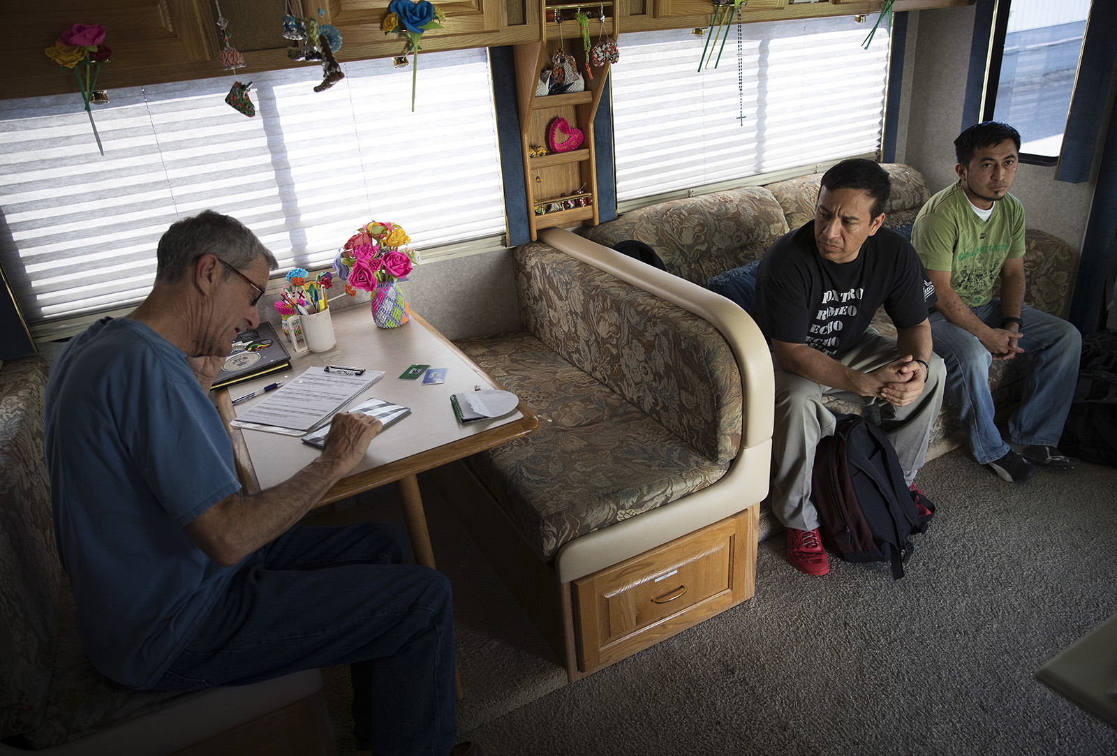 caption: Scott Goddard, left, assists Selso Olivan and Alexi Martinez, right, in the Advocates for Immigrants in Detention Northwest R.V., the "Welcome Center," outside of the Northwest Detention Center in Tacoma. Tap on this image for more photos.