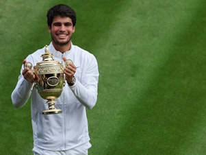 caption: Carlos Alcaraz with his shiny new trophy.