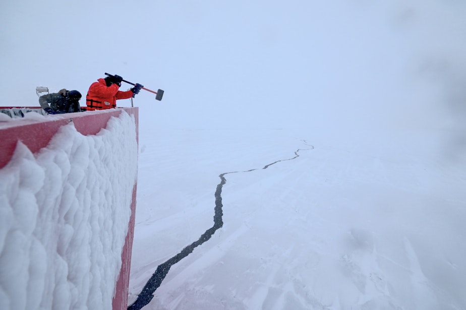 caption: Petty Officer 1st Class Wahkene Kitchenmaster, a member of the Coast Guard Cutter Polar Star (WAGB 10) deck department, works in below freezing temperatures to remove ice from the ship’s hull while underway in the Chukchi Sea.