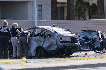 caption: Las Vegas Metro Police investigators work at the scene of a fatal crash Tuesday. Police say Las Vegas Raiders wide receiver Henry Ruggs III was involved in a fiery crash that left a woman dead and Ruggs and his female passenger injured.