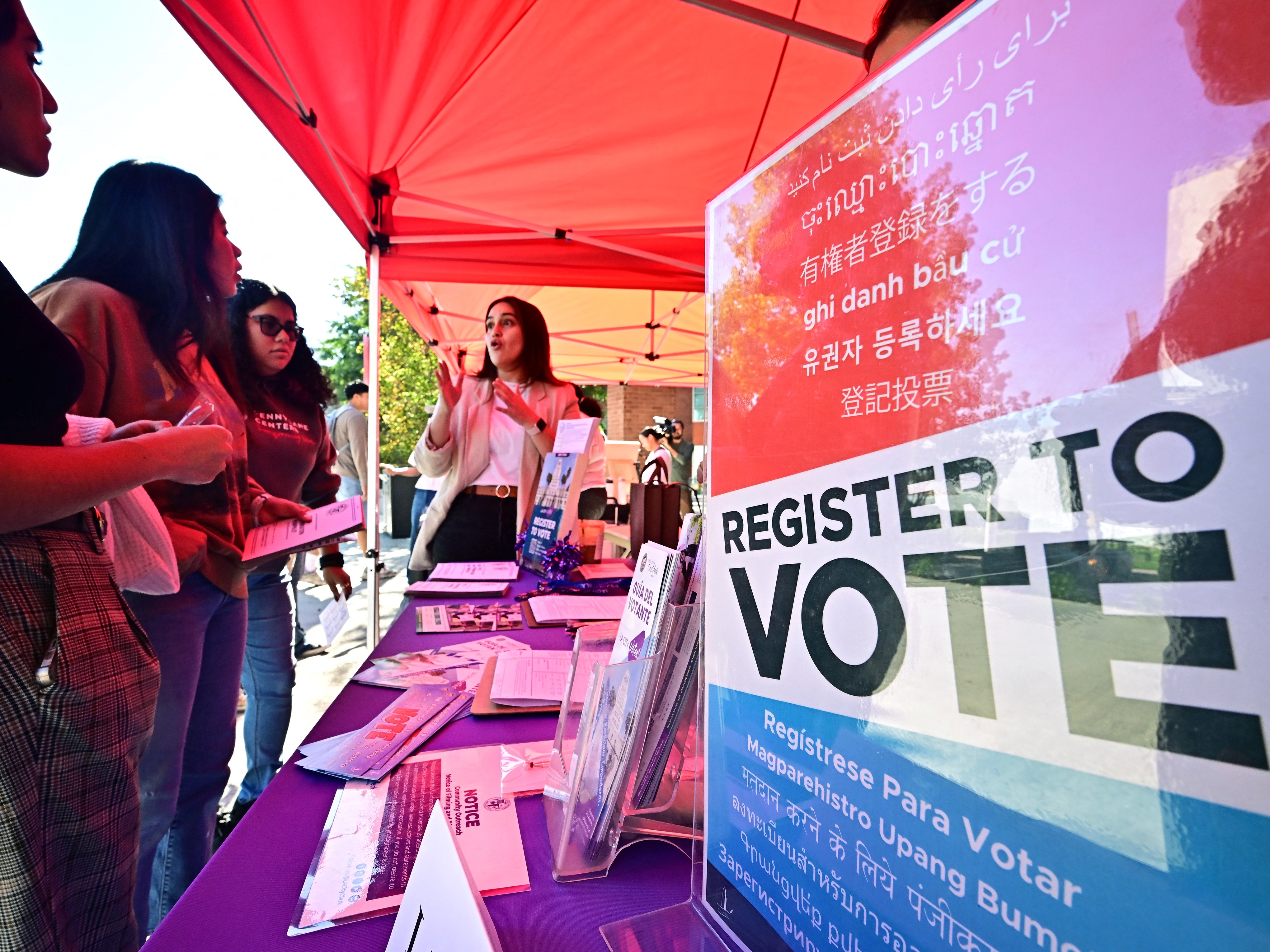 caption: Potential young voters get information at a voter registration desk at California State University, Los Angeles, on Oct. 22, 2024. The Republican-backed SAVE Act would add documentary proof-of-citizenship requirements to voter registration.